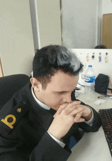 a man sitting at a desk with a bottle of aquafina water next to him