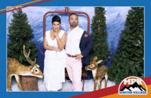 a man and a woman pose for a photo in front of a winter village logo