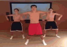 three men are dancing in front of a large screen .