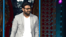 a man wearing glasses and a grey jacket is standing in front of a stage
