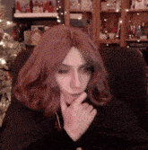 a woman with long red hair is sitting in front of a christmas tree