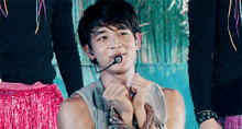 a man with a microphone in his mouth is making a heart with his hands