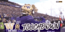 a football player wearing a helmet with the letter w on it stands in front of a sign that says touchdown