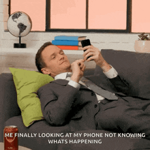 a man laying on a couch looking at his phone