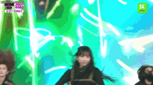 a girl is dancing on a stage with a green background and a kcon logo in the corner