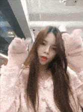 a woman wearing a pink sweater and gloves with cat paws on them