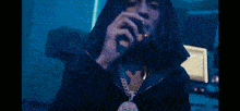 a man with long hair is smoking a cigarette in a room .
