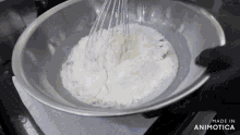 a person is whisking flour in a metal bowl with the words made in animotica written on the bottom