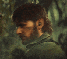 a man with a beard and ear buds looks at something