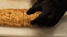a person in black gloves is cutting a piece of food on a cutting board made in animatica