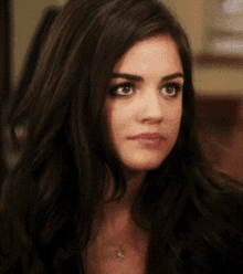 a close up of a woman 's face with long dark hair and a necklace
