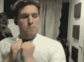 a man in a white shirt adjusts his tie in front of a mirror