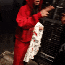 a person wearing a red hoodie is holding a white shirt