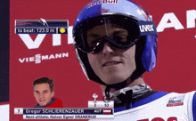 a man wearing a red bull helmet and uvex goggles looks at the camera