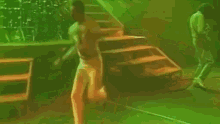 a man without a shirt is dancing on a stage in front of stairs .