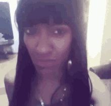 a woman with long black hair and bangs is making a face