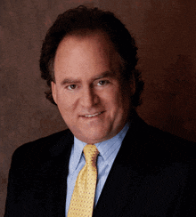 a man wearing a suit and tie is smiling for the camera