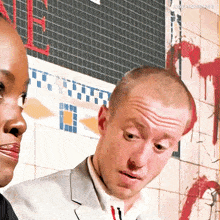 a man and a woman are standing in front of a tiled wall with the word loser quinn written on it