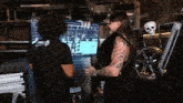 a man with a tattoo on his arm is standing next to another man playing a video game