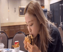a woman is sitting at a table eating a hamburger