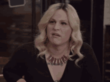 a woman wearing a purple necklace is making a face
