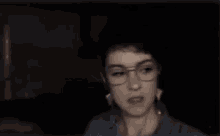 a man wearing glasses is laughing in a dark room in a blurry photo .