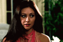 a woman with long hair is wearing a pink top and scarf .