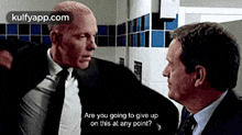 a man in a suit and tie is talking to another man .
