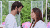 a man and a woman are looking into each other 's eyes while standing next to each other .
