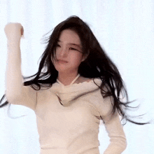 a woman with long black hair is dancing in front of a white curtain .