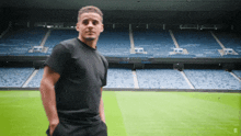 a man in a black shirt is standing in an empty stadium