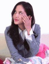 a woman in a grey sweater is sitting on a couch with her hand on her face