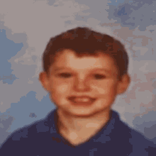 a young boy in a blue shirt is making a funny face for a picture .