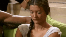 a woman in a braid is sitting on a green couch .