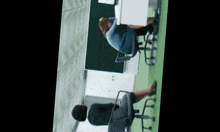 a man sits at a desk in a classroom with his head on his arm