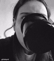 a black and white photo of a woman drinking from a large cup