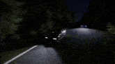 a car is driving down a road at night with its headlights on