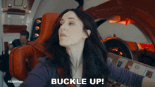 a woman sitting in a chair with the words buckle up above her