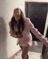 a woman in a pink suit is standing on stairs