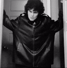a man in a leather jacket is standing in a doorway