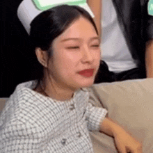 a woman is sitting on a couch with her eyes closed and wearing a nurse 's hat .