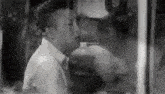 a black and white photo of a man behind a glass