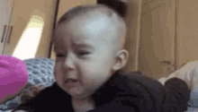 a baby is crying while laying on a bed .