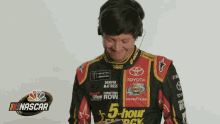 a man wearing headphones and a nascar shirt looks at his phone