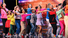 a group of children are dancing on a stage with a nbc logo in the corner