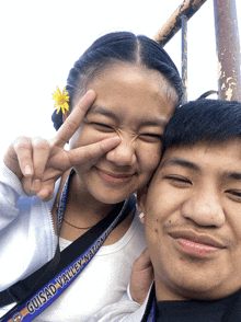 a girl with a flower in her hair is giving a peace sign with a man