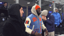a man in a varsity jacket has the number 12 on his arm