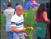 a man holding a bunch of sunflowers in front of a red bull flag