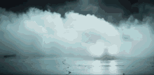 a car with its headlights on is driving through a cloud of smoke .