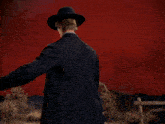 a man in a suit and hat holding a gun